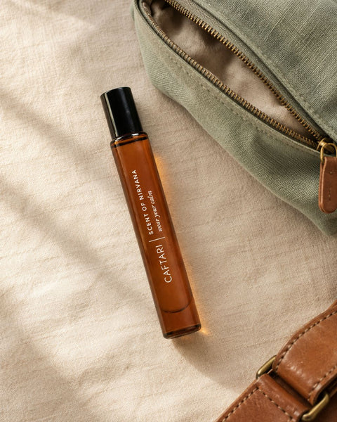 Caftari Scent of Nirvana perfume oil on cream linen beside a sage travel pouch