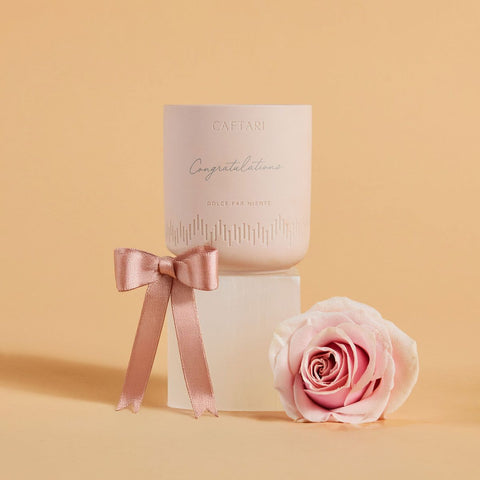 Personalized Caftari Dolce Far Niente candle engraved with Congratulations, beside a pink ribbon and rose