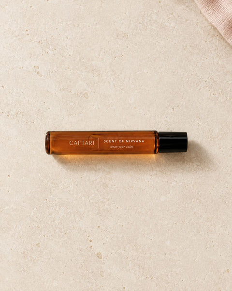 Full Caftari Scent of Nirvana perfume oil bottle lying horizontally on warm limestone