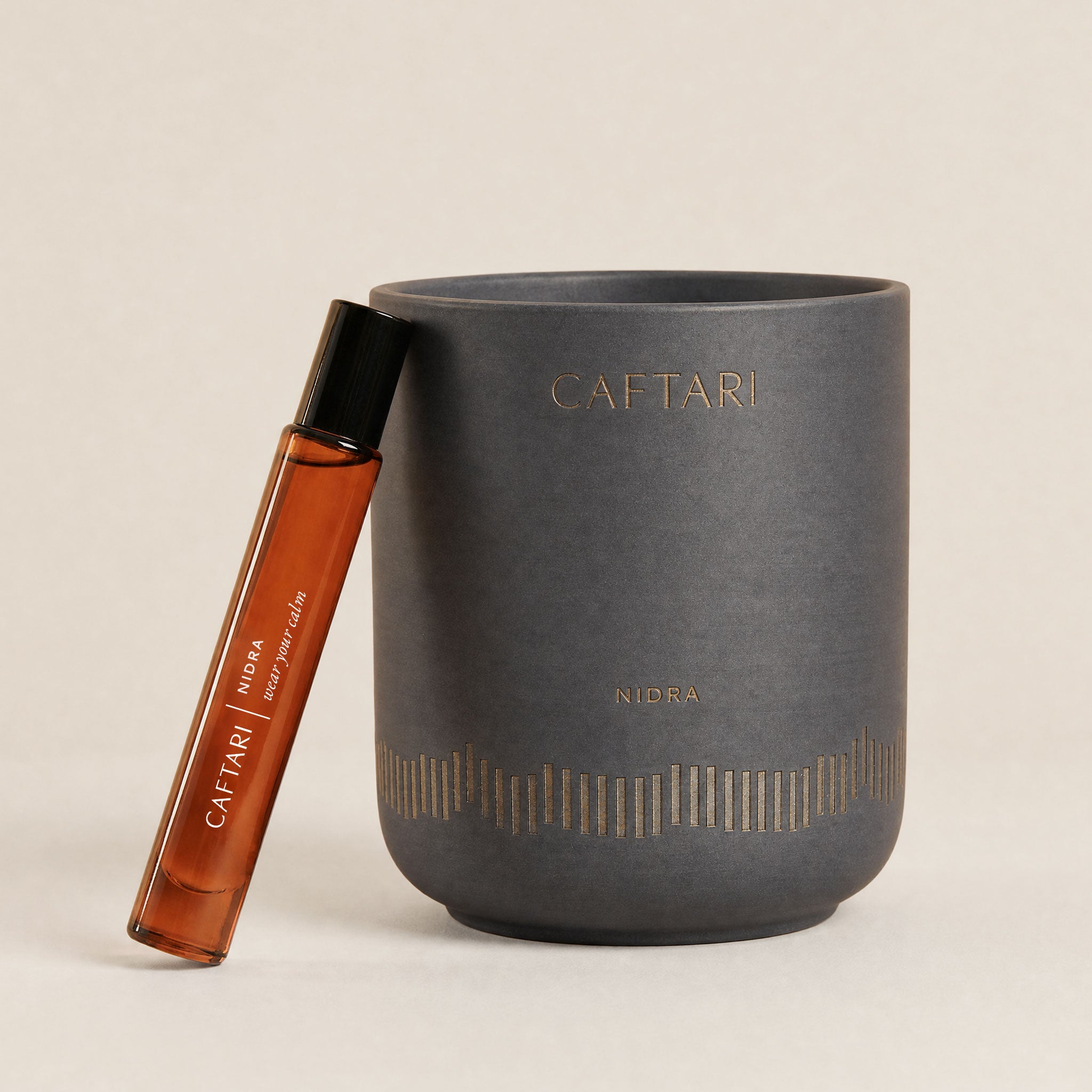 Nidra candle and rollerball perfume oil on a nightstand